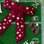 Collection of earrings and a red bow with decorative pins on a green surface with white lines.