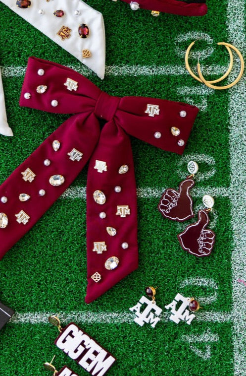 Collection of earrings and a red bow with decorative pins on a green surface with white lines.
