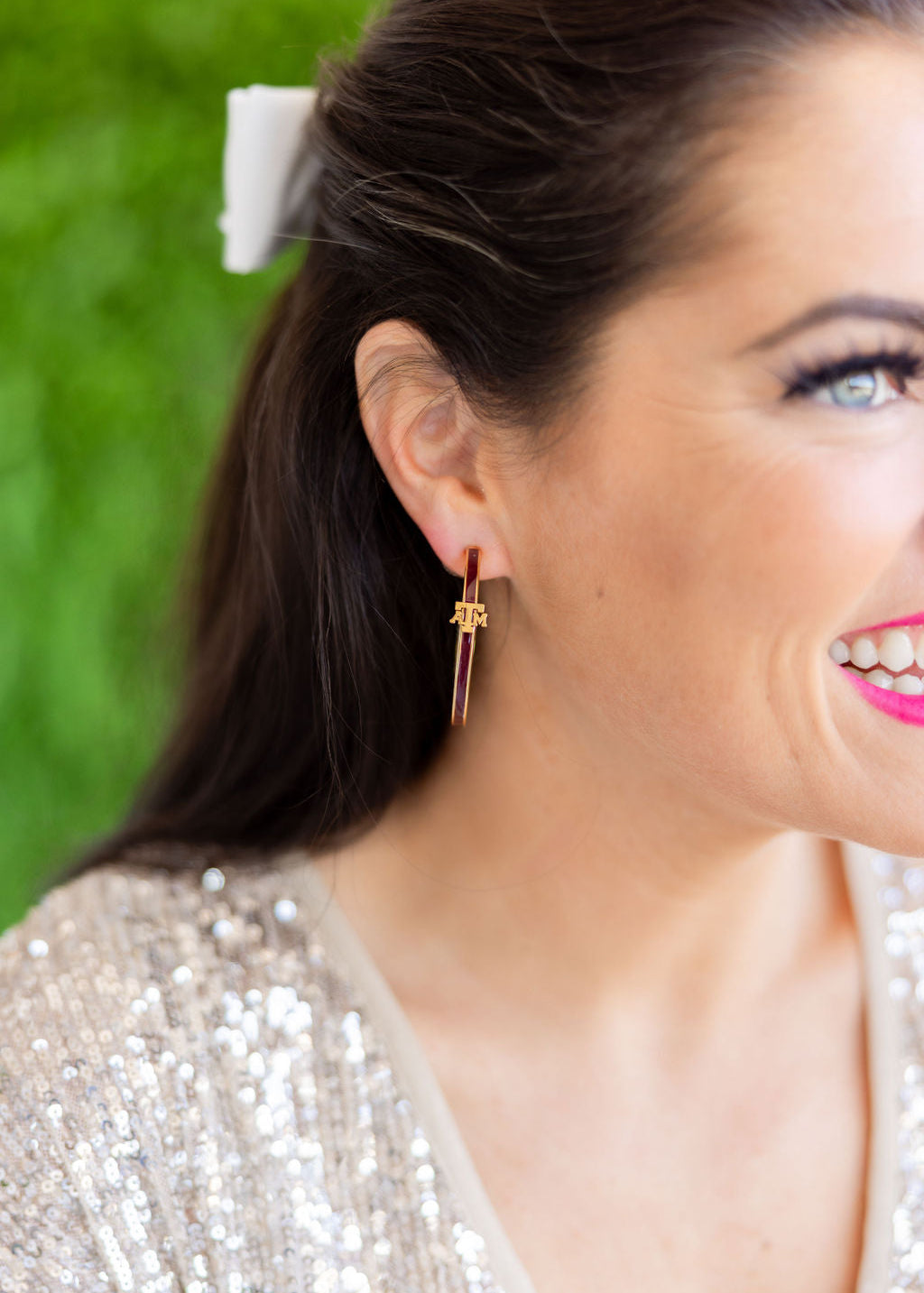 Close-up of a woman wearing a gold earring with a green blurred background