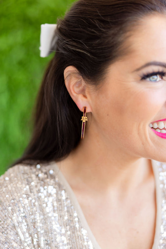 Close-up of a woman wearing a gold earring with a green blurred background