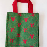 Green tote bag with red bow pattern on a white background