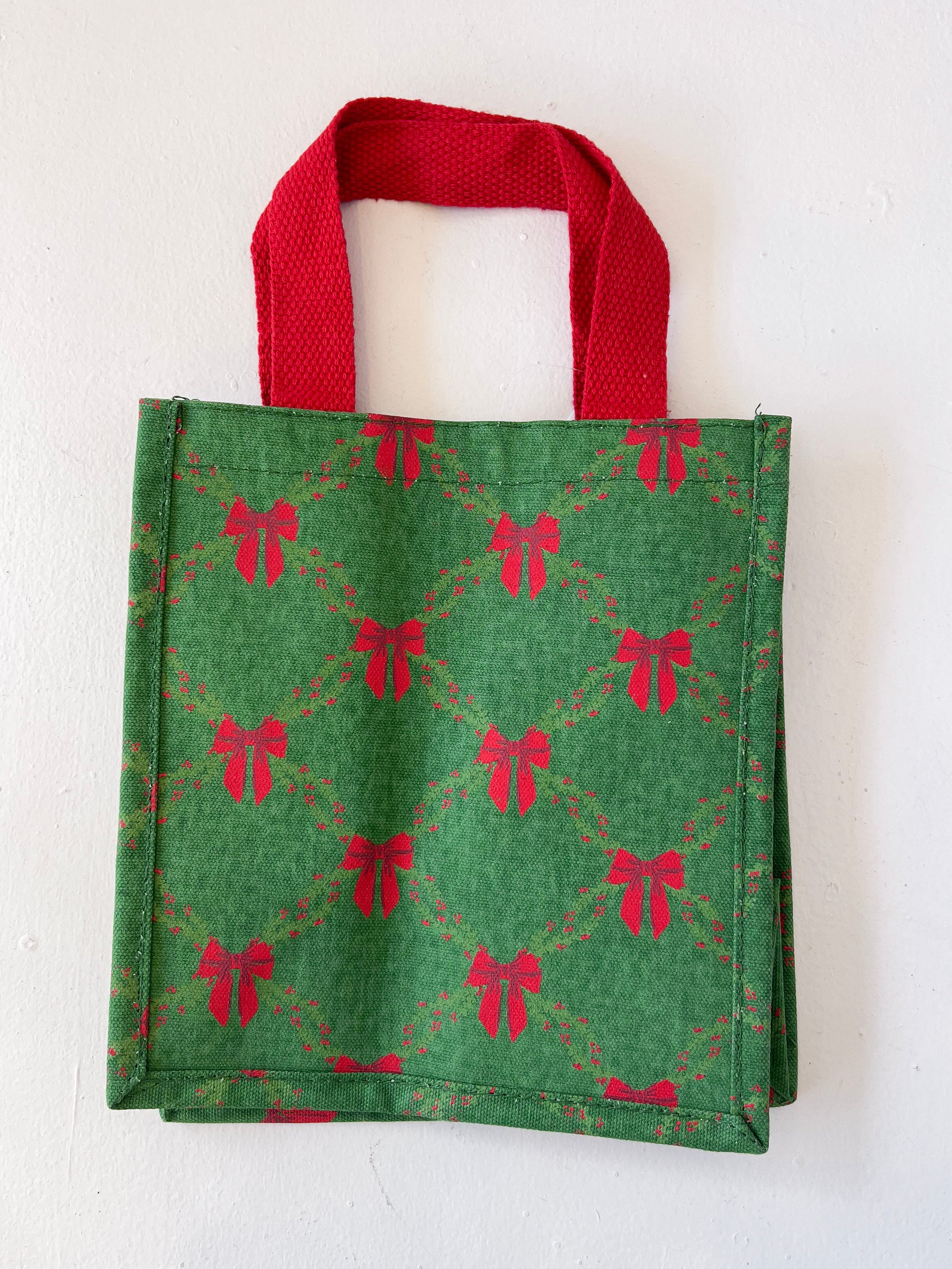 Green tote bag with red bow pattern on a white background