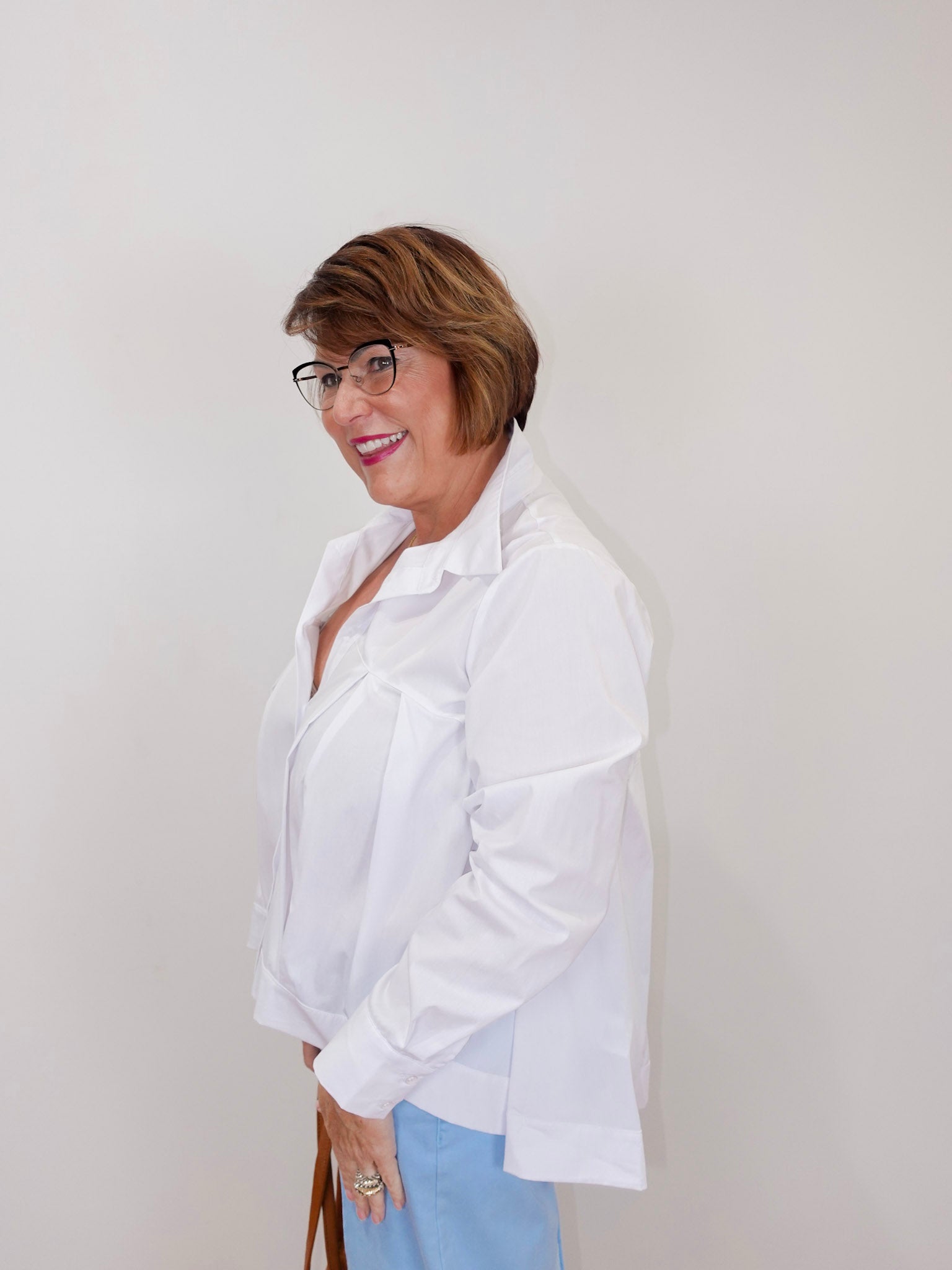 Woman wearing a white A-line blouse with a button-front design and relaxed fit.