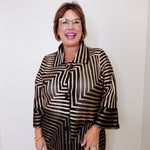 Woman wearing a black and gold patterned blouse against a white background