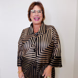 Woman wearing a black and gold patterned blouse against a white background