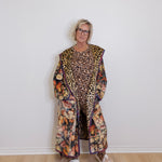 Person wearing a long, patterned coat with a leopard print design on a white background