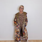 Person wearing a long, patterned coat with a leopard print design on a white background