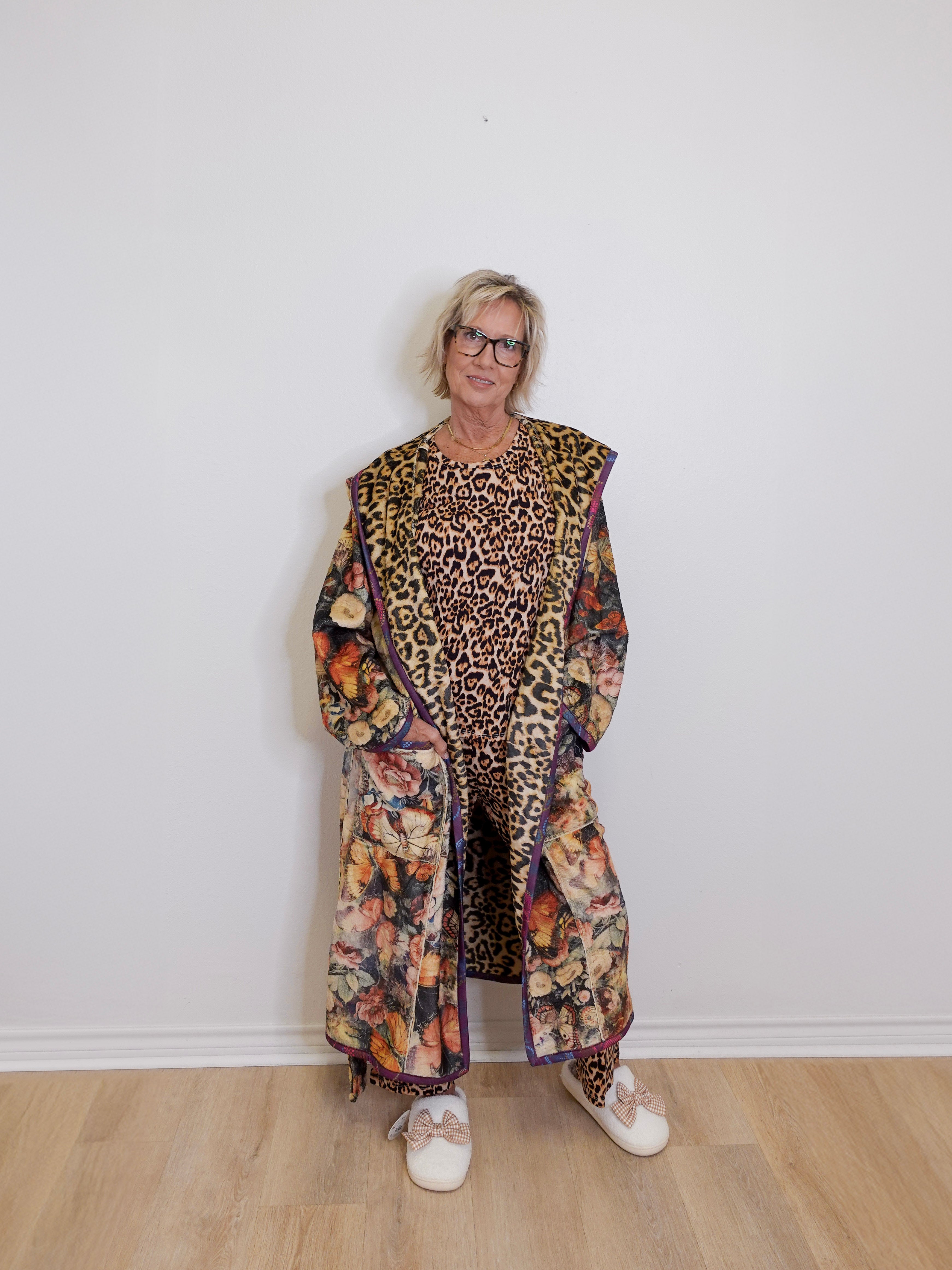 Person wearing a long, patterned coat with a leopard print design on a white background