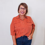 Woman wearing an orange shirt and blue jeans against a white background