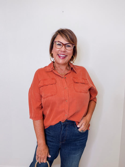 Woman wearing an orange shirt and blue jeans against a white background