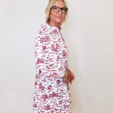 Woman wearing a white dress with red patterns against a plain background
