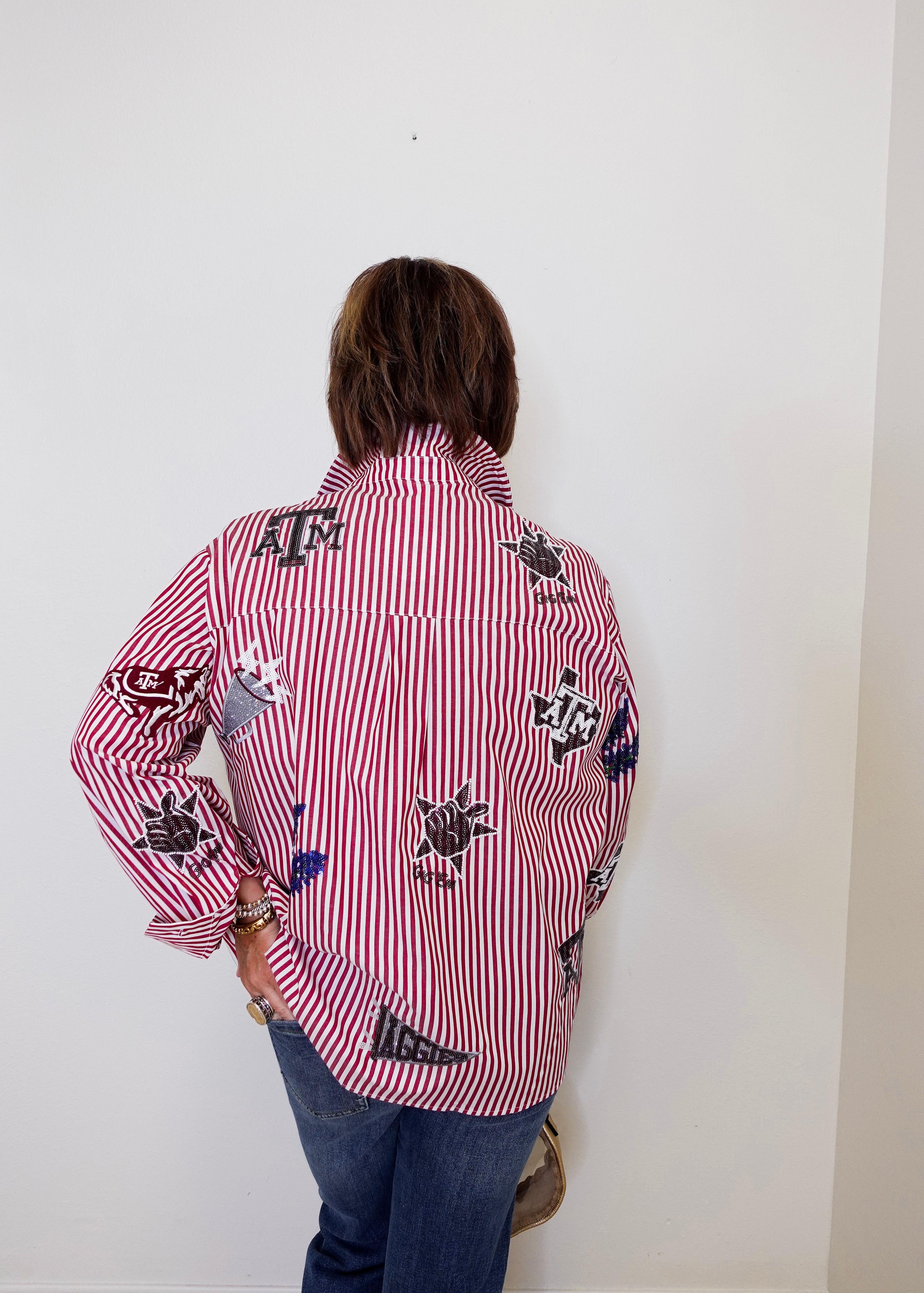Person wearing a red and white striped shirt with black designs against a white wall