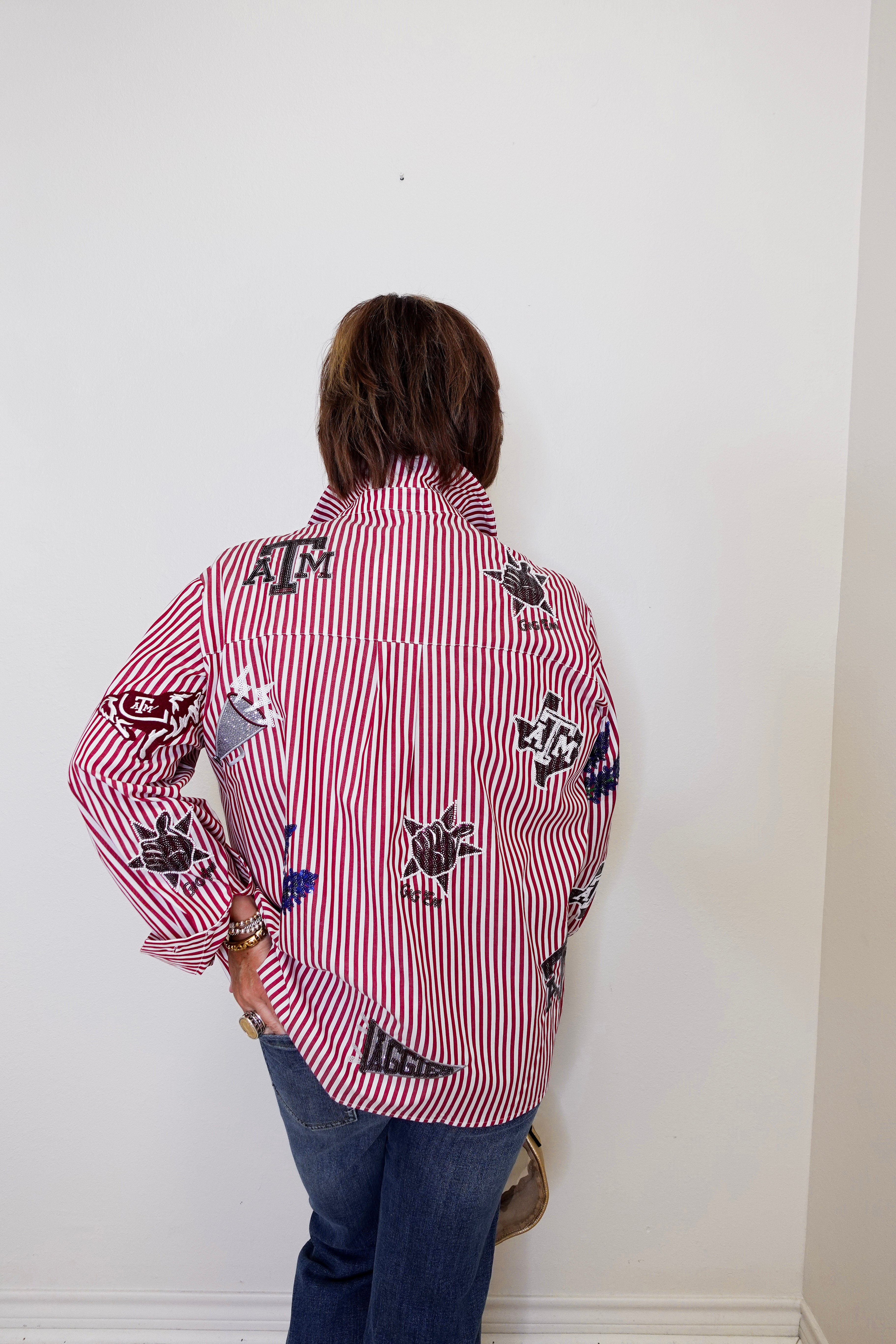 Person wearing a red and white striped shirt with black designs against a white wall