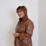 Woman wearing a brown leather jacket against a white wall