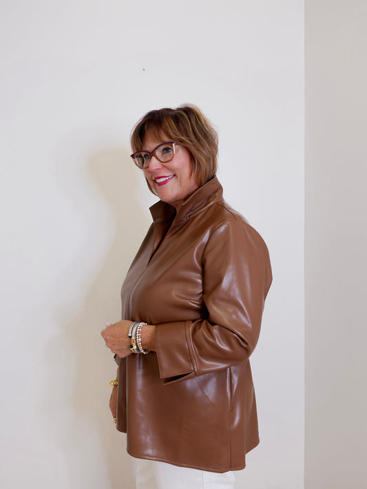 Woman wearing a brown leather jacket against a white wall