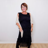 Woman wearing a black dress with sheer sleeves against a white wall