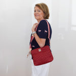 Woman holding a red quilted handbag against a white background
