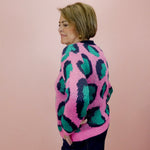 Person wearing a colorful sweater with a pink and green pattern against a plain background