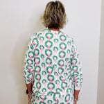 Person wearing a festive dress with wreath and bow pattern against a white background