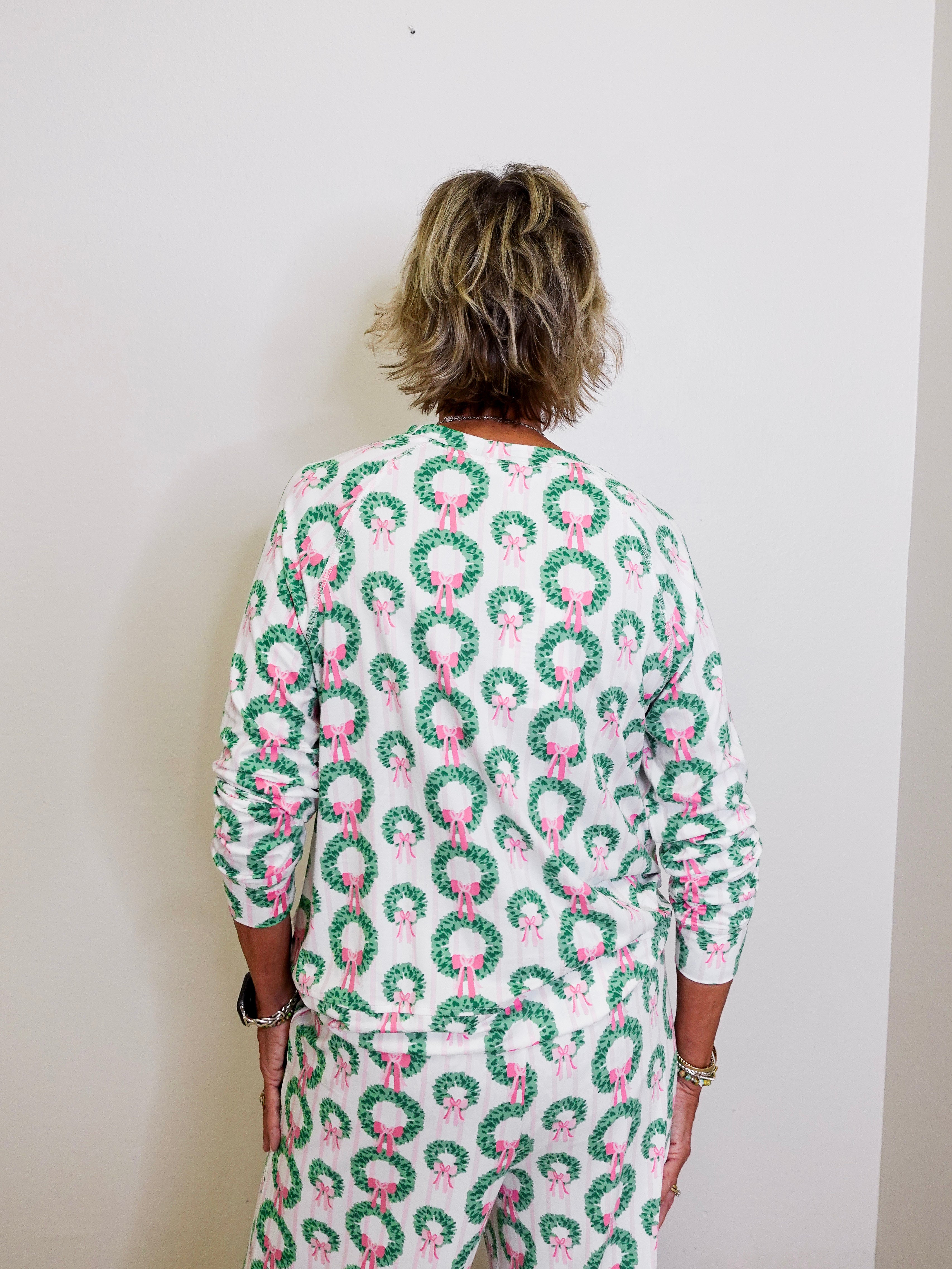 Person wearing a festive dress with wreath and bow pattern against a white background