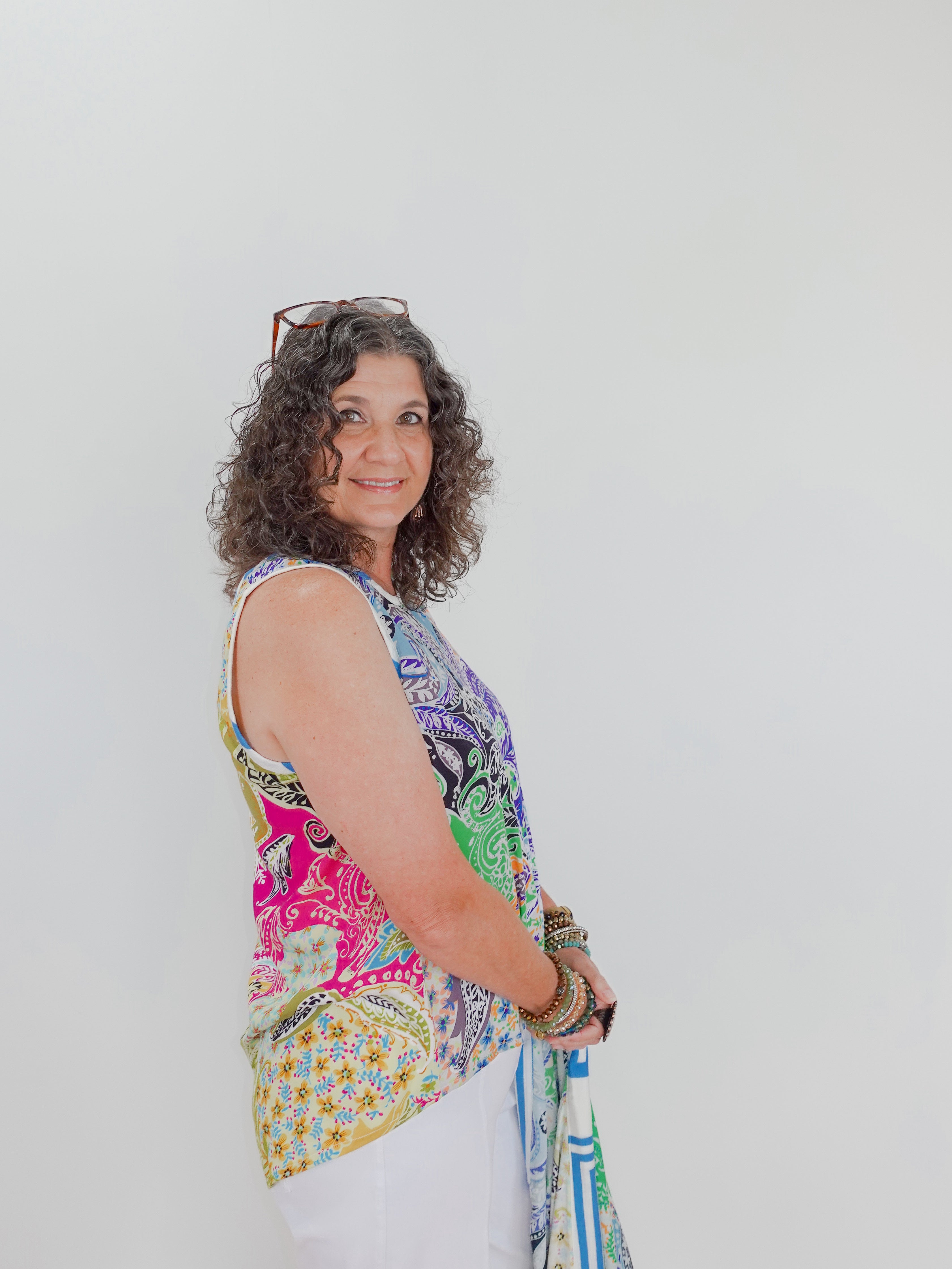 Woman wearing a colorful sleeveless top with a white background