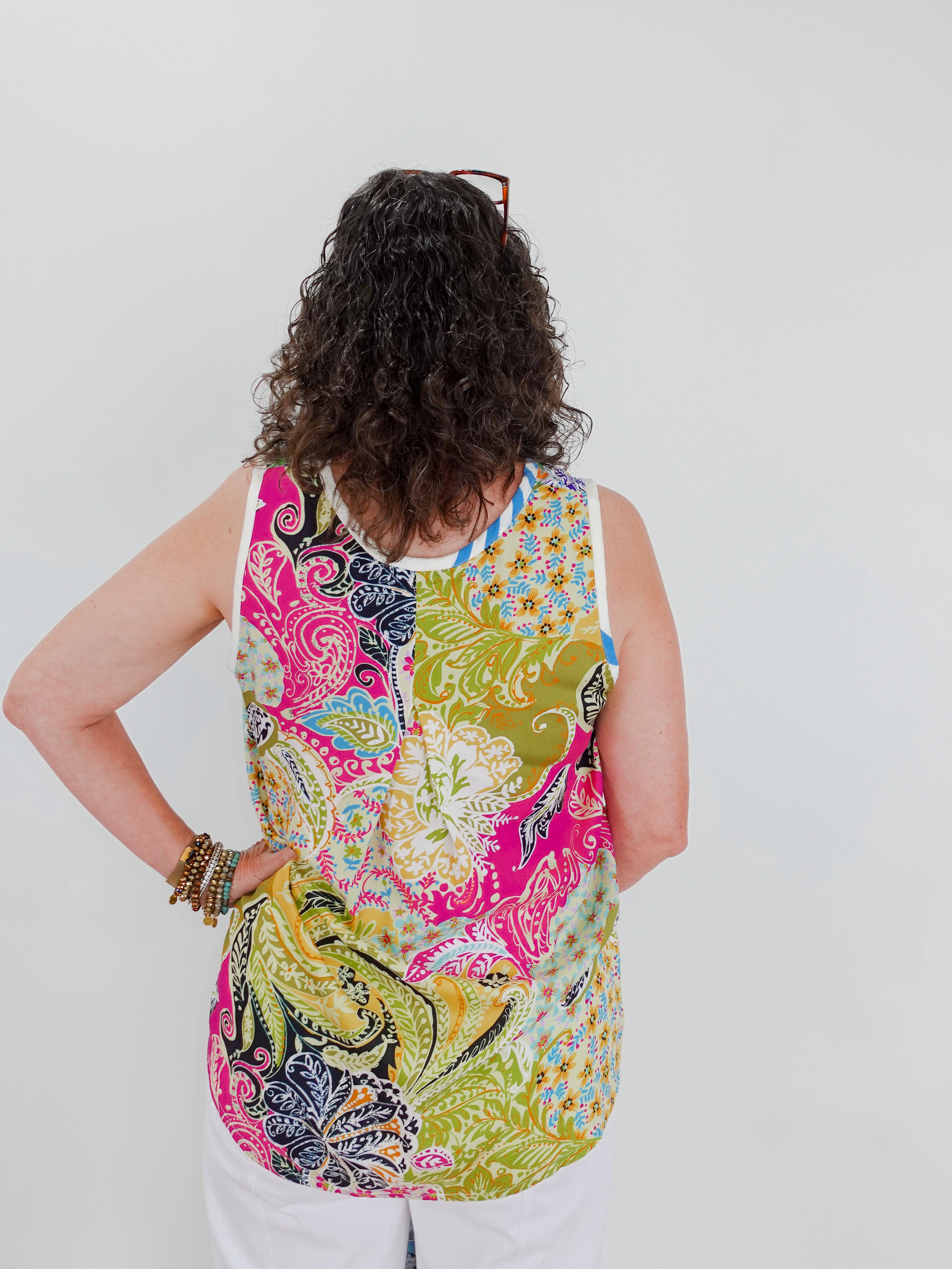 Person wearing a colorful patterned sleeveless top against a white background