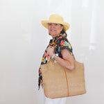 Woman holding a large woven bag against a white background