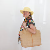 Woman holding a large woven bag against a white background