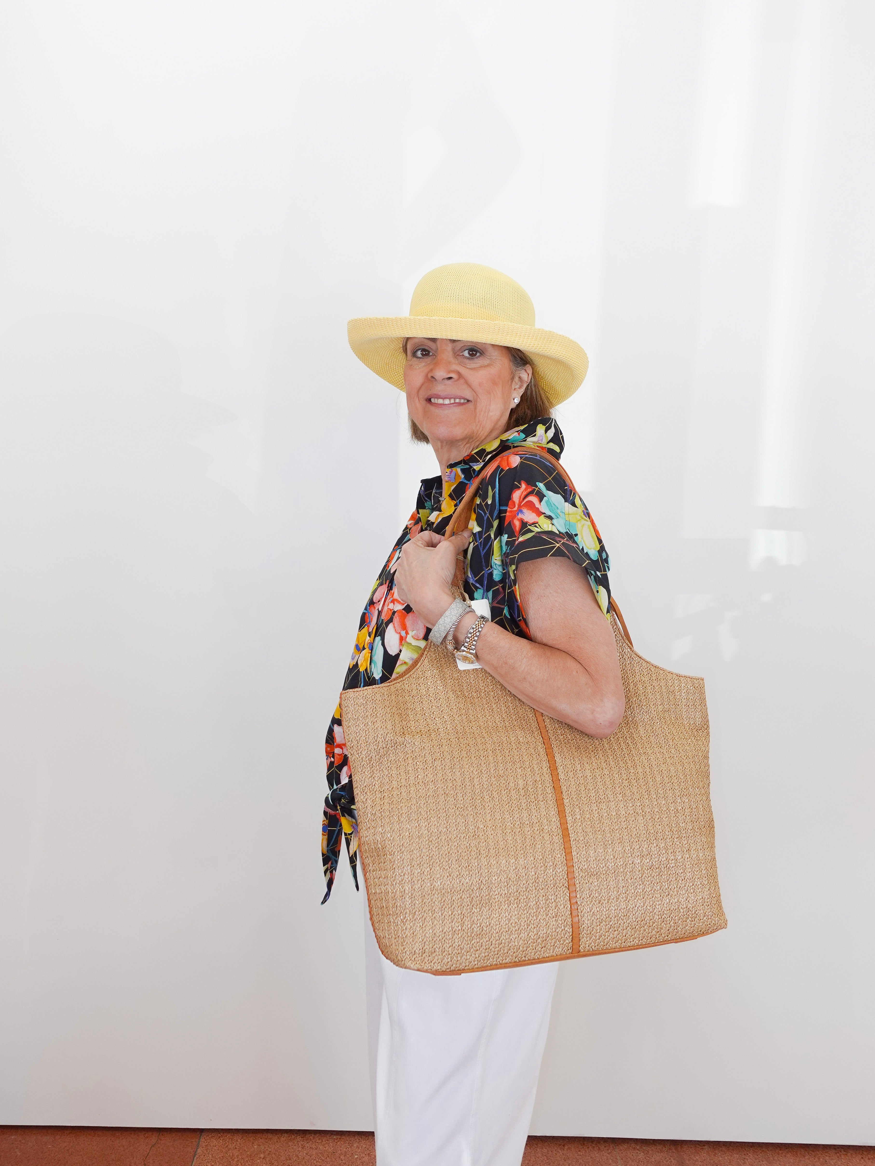 Woman holding a large woven bag against a white background