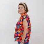 Woman wearing a colorful floral shirt against a white background