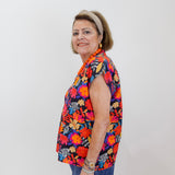 Woman wearing a colorful floral shirt against a white background