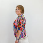 Woman wearing a colorful floral blouse against a white background