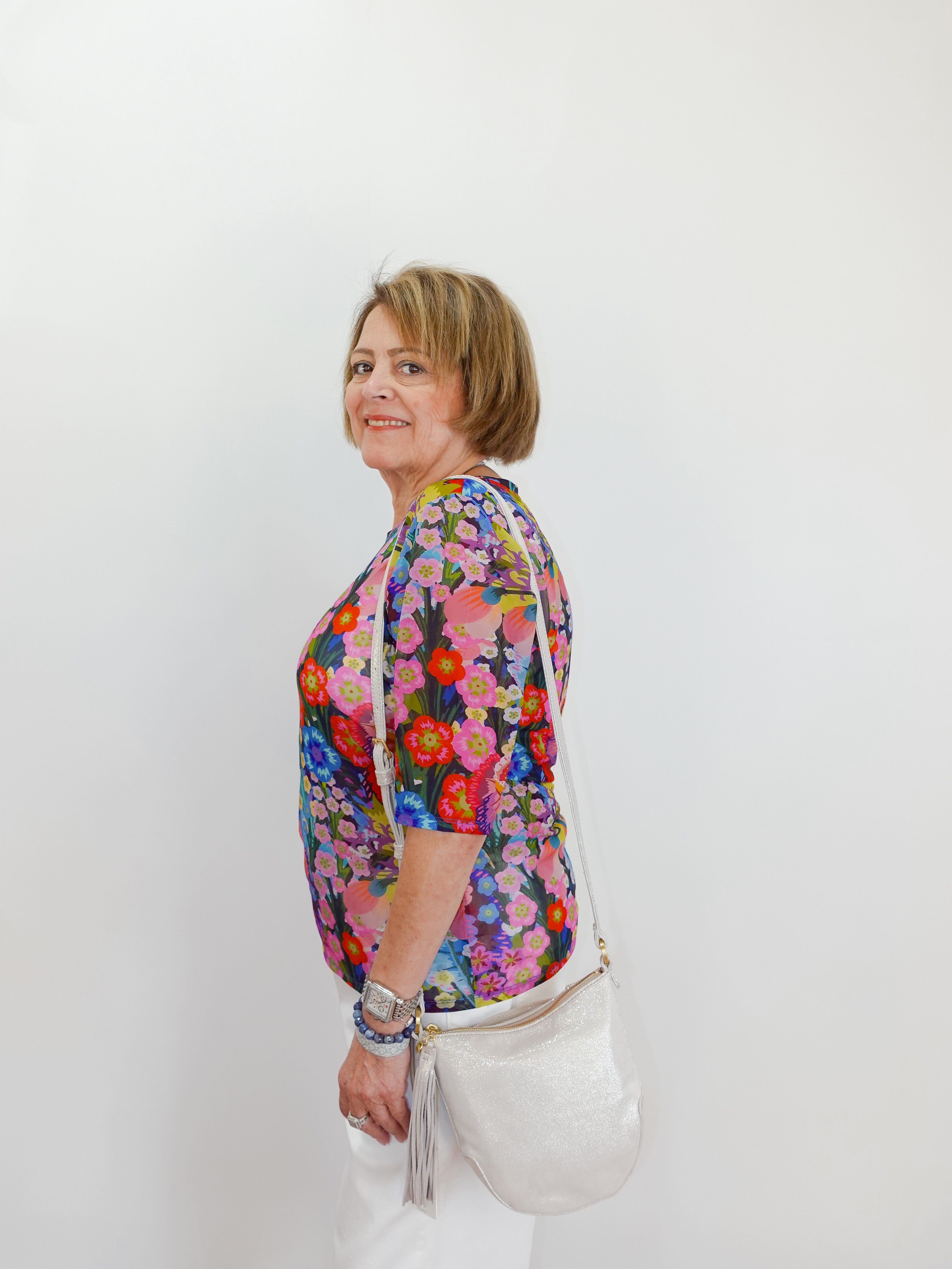 Woman wearing a colorful floral blouse against a white background