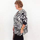 Woman wearing a black and white patterned blouse against a white background
