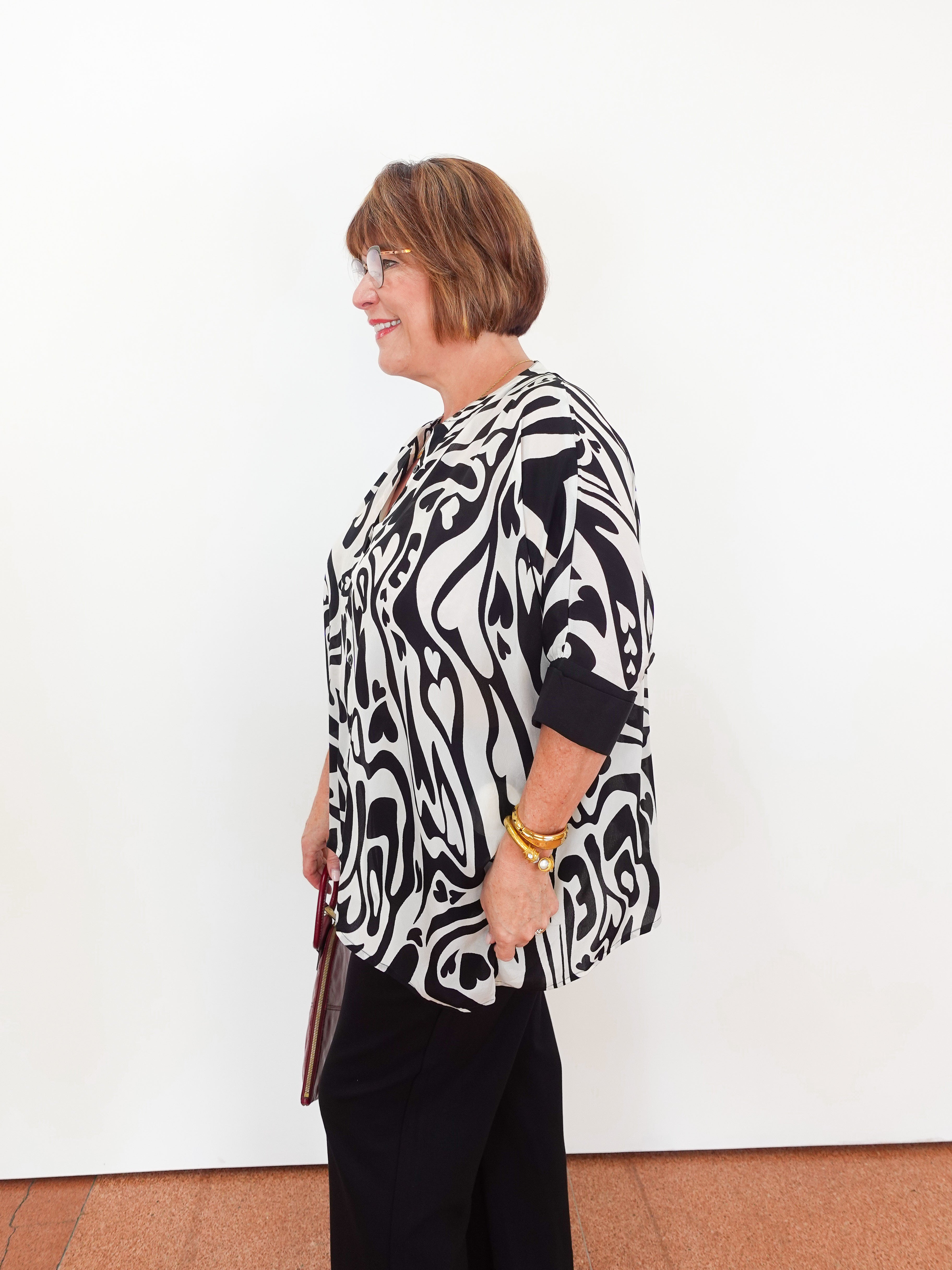 Woman wearing a black and white patterned blouse against a white background