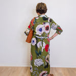Person wearing a floral dress with a plain white wall background