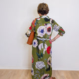 Person wearing a floral dress with a plain white wall background