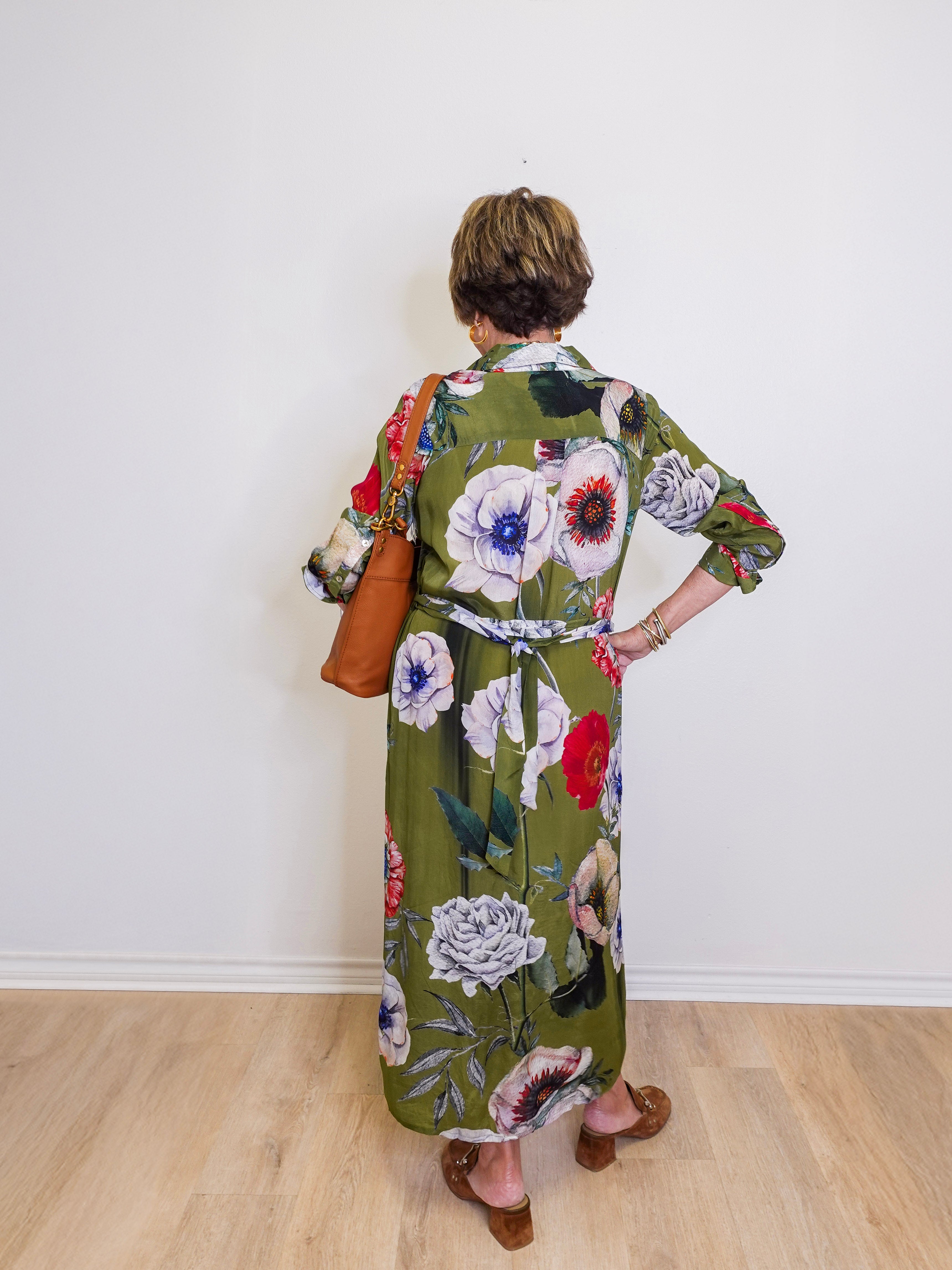 Person wearing a floral dress with a plain white wall background