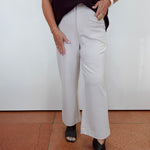 A person wearing light beige wide-leg cropped pants, a dark burgundy ribbed short-sleeve top, and black peep-toe heels, standing against a white wall with terracotta tiled flooring.
