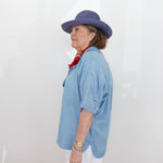Person wearing a blue hat and light blue shirt against a white background
