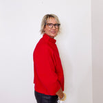 Woman wearing a red sweater and black leather pants against a white background
