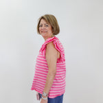 Woman wearing a pink striped sleeveless top and blue pants against a white background