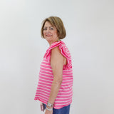 Woman wearing a pink striped sleeveless top and blue pants against a white background