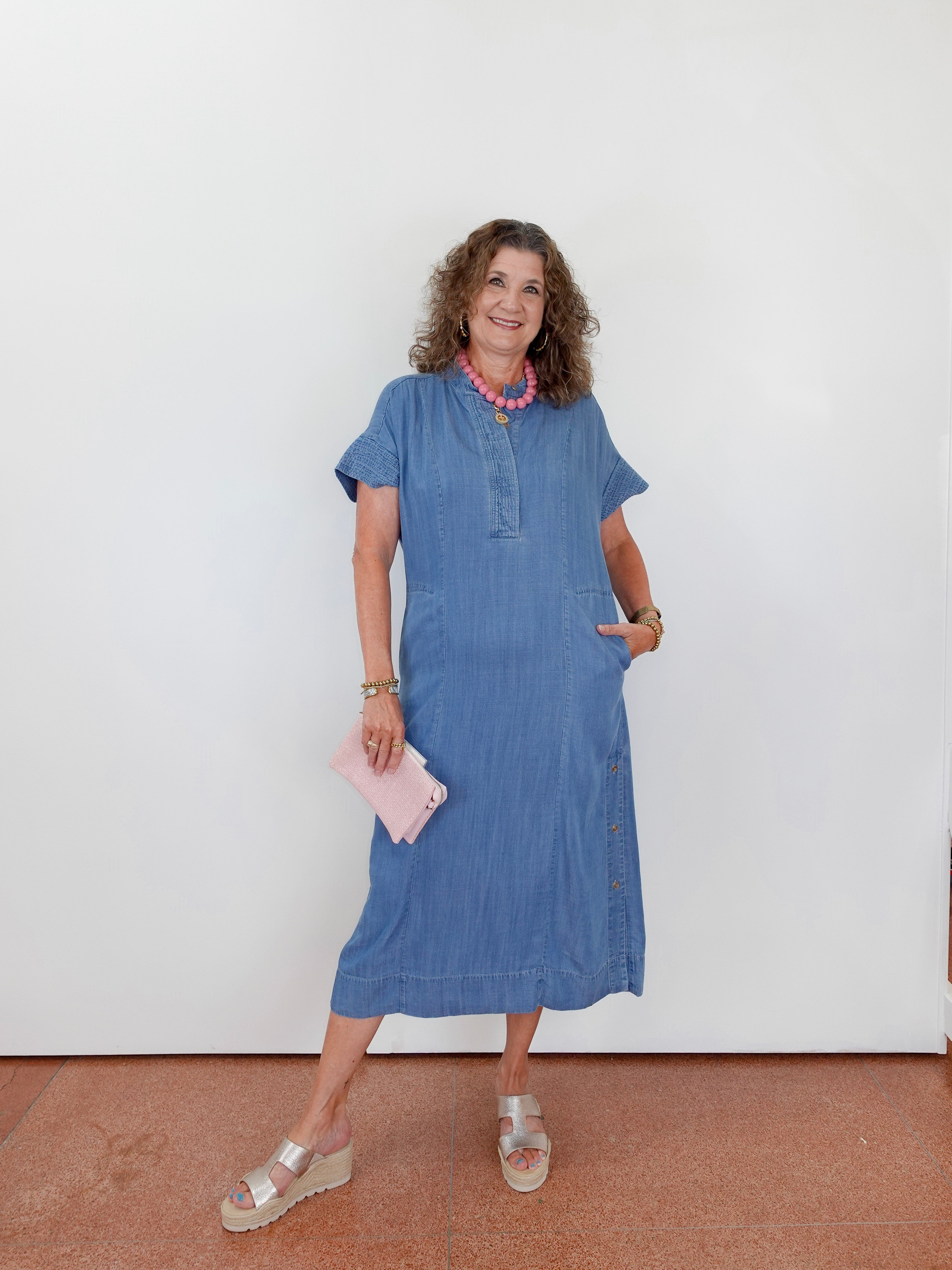 Woman in a blue dress standing against a white wall