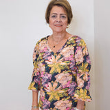 Woman wearing a floral blouse against a plain background