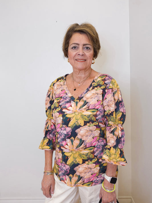 Woman wearing a floral blouse against a plain background