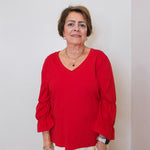 Woman wearing a red blouse against a plain background