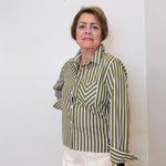 Woman wearing a green and white striped shirt against a white wall
