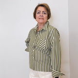 Woman wearing a green and white striped shirt against a white wall