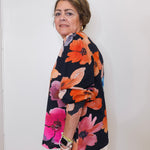 Woman wearing a colorful floral jacket against a white background